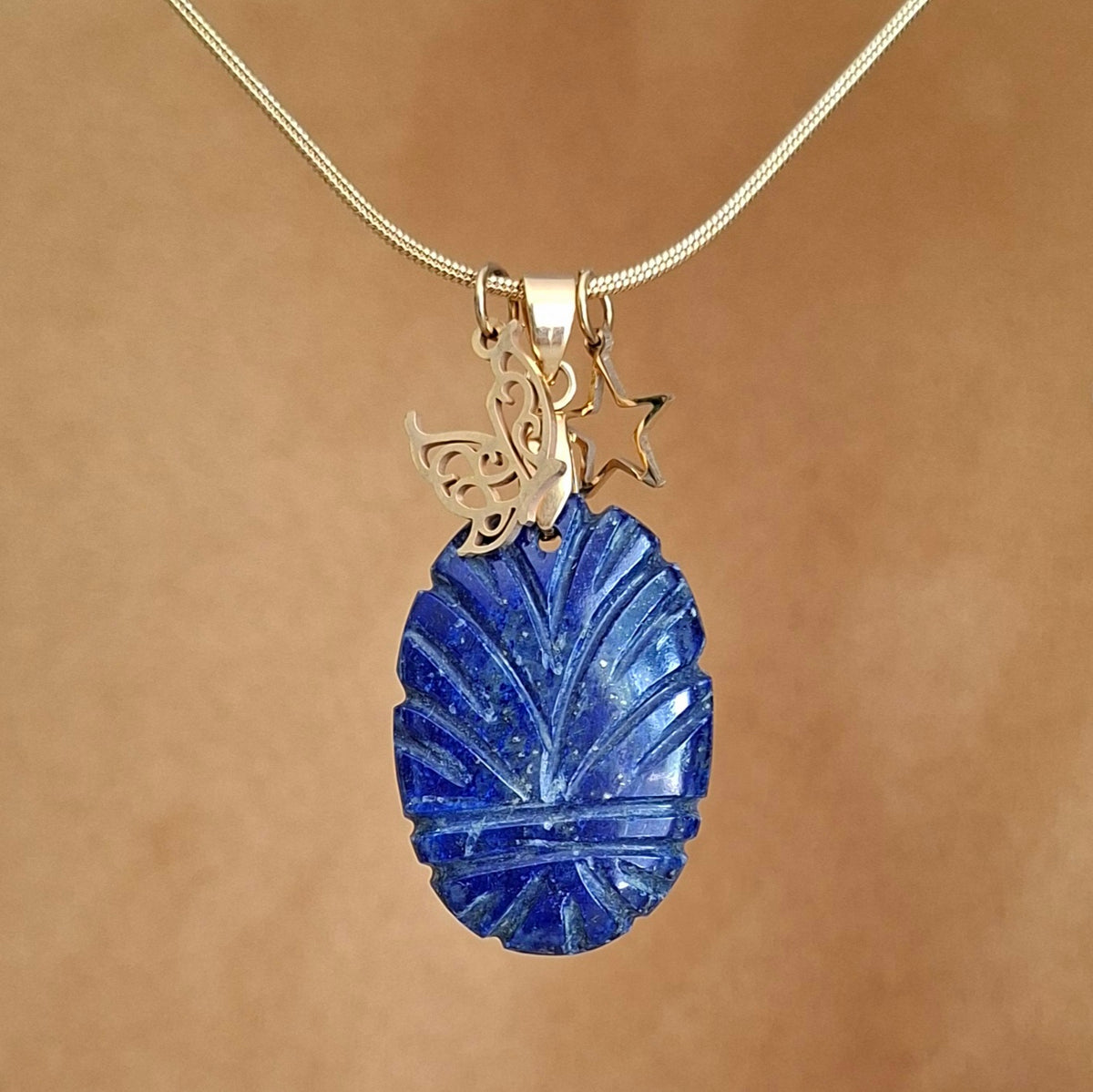 Collier lapis-lazuli ovale ciselé avec breloques étoile et papillon.