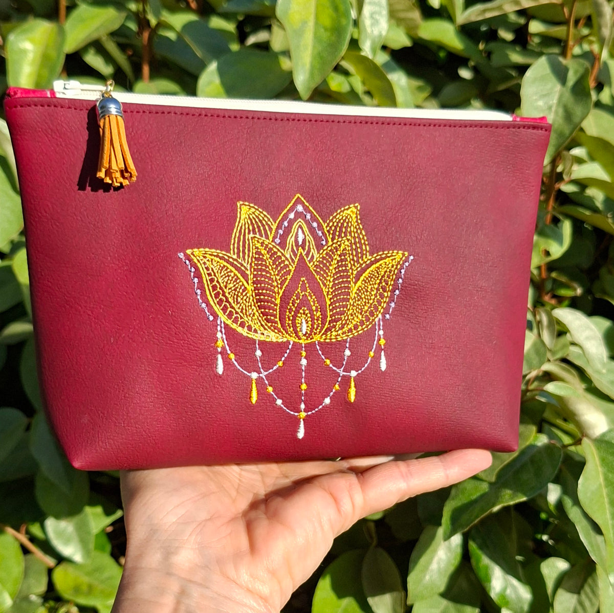 Trousse femme brodée lotus en simili cuir bordeaux tenue en main