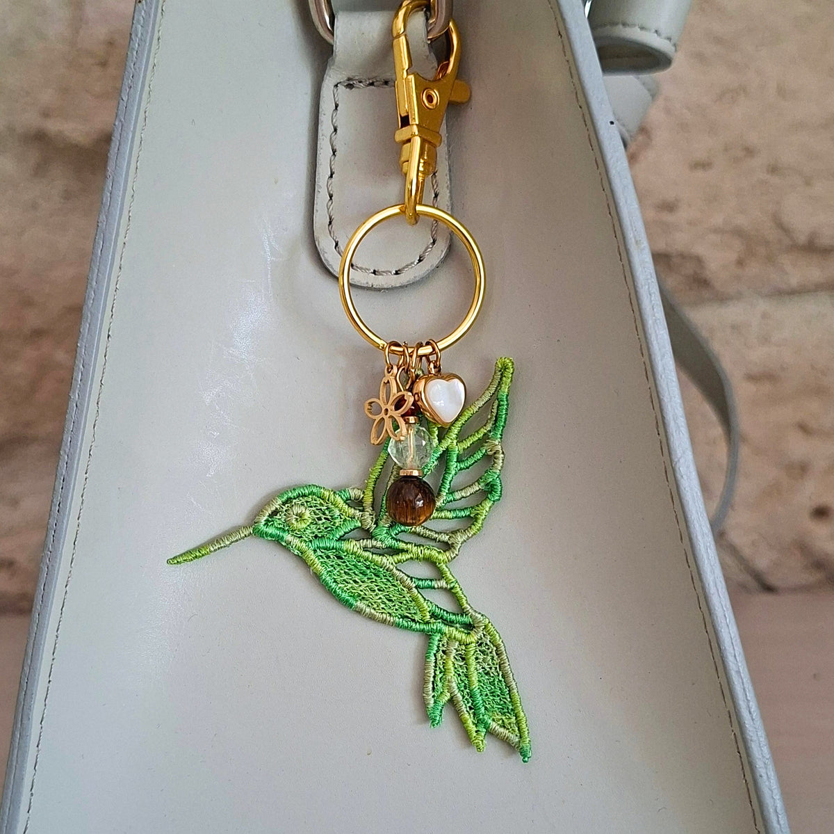 Bijou de sac Colibri Joie de vivre vert porté sur un sac avec pierres naturelles et détails dorés