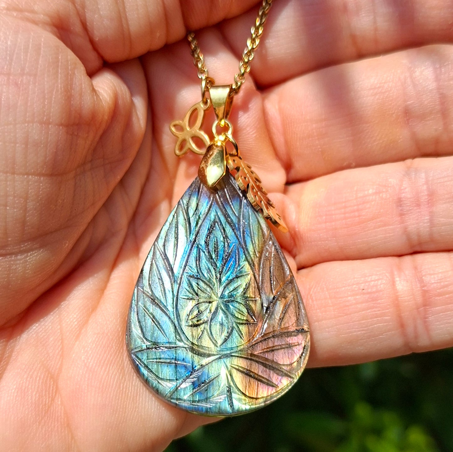 Collier en labradorite ciselée motif feuillage présenté dans la main