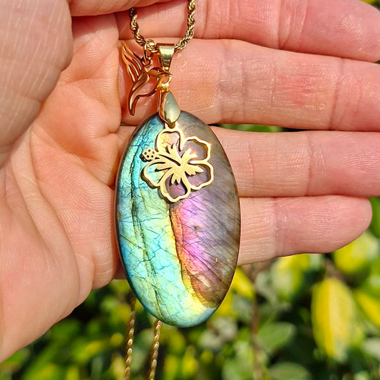 Collier en labradorite ovale tenu dans la main montrant ses reflets verts et violets