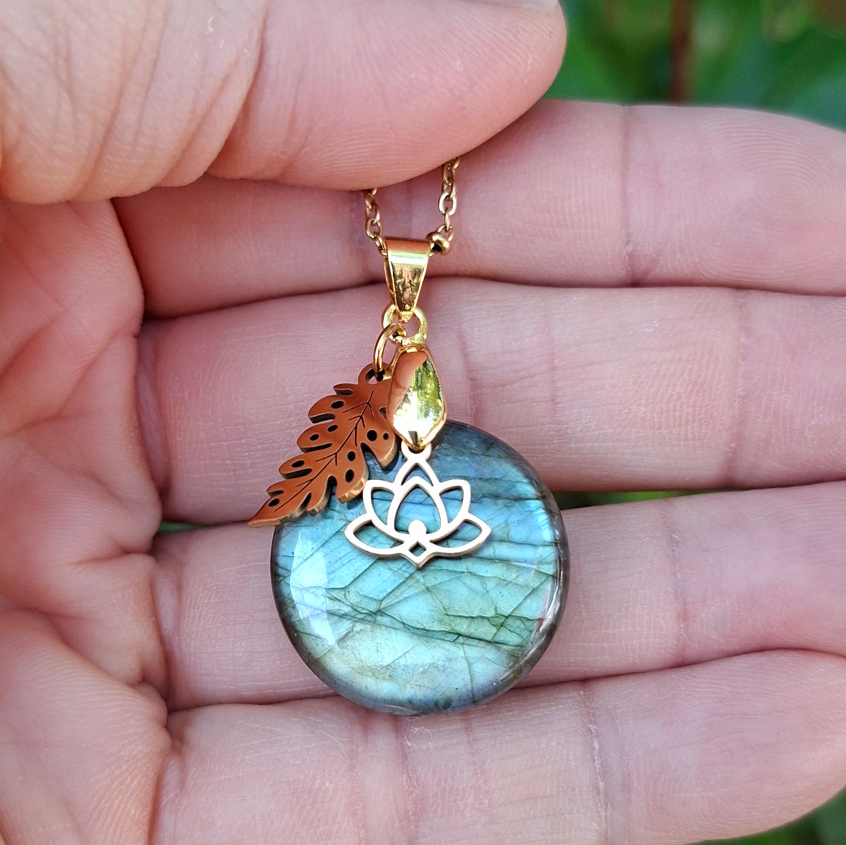 Collier en labradorite ronde naturelle aux reflets vert métallisé présenté dans la main.