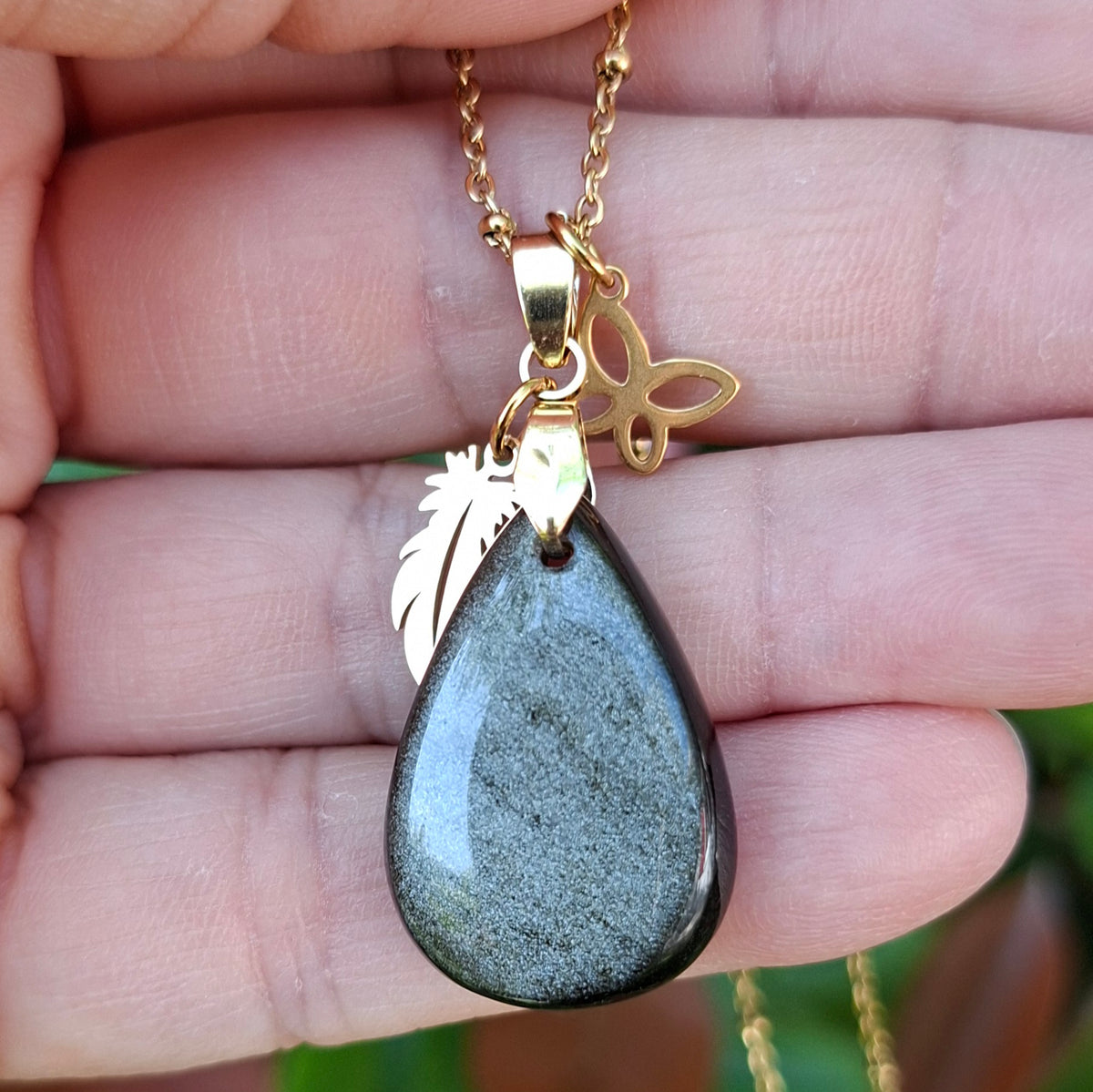 Collier en obsidienne dorée naturelle aux reflets dorés présenté dans la main.