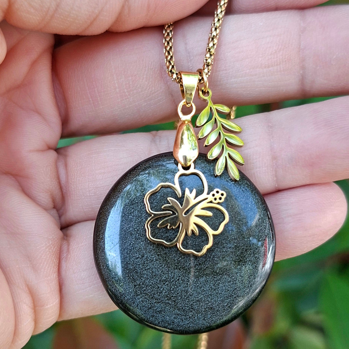 Collier en obsidienne dorée ronde naturelle présenté dans la main.