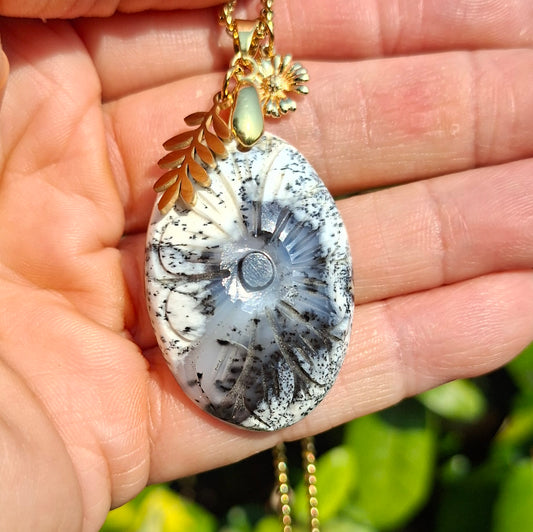 Collier en opale dendritique tenu dans la main montrant ses inclusions naturelles et sa ciselure