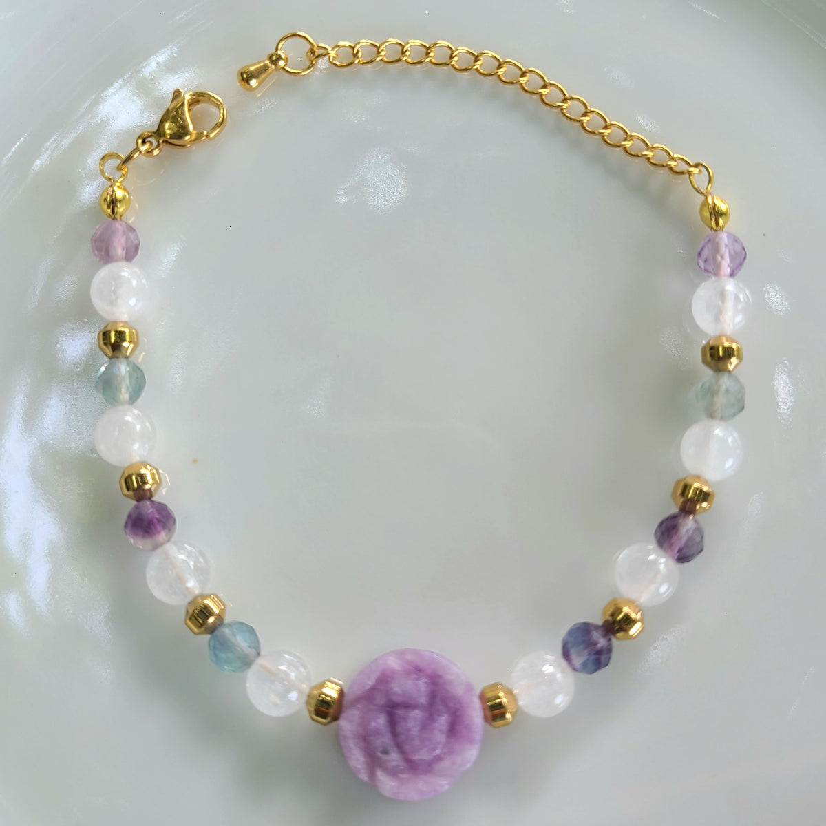 Bracelet en lépidolite taillée en fleur, fluorite facettée et quartz laiteux, avec perles intercalaires en hématite dorée à l’or fin.