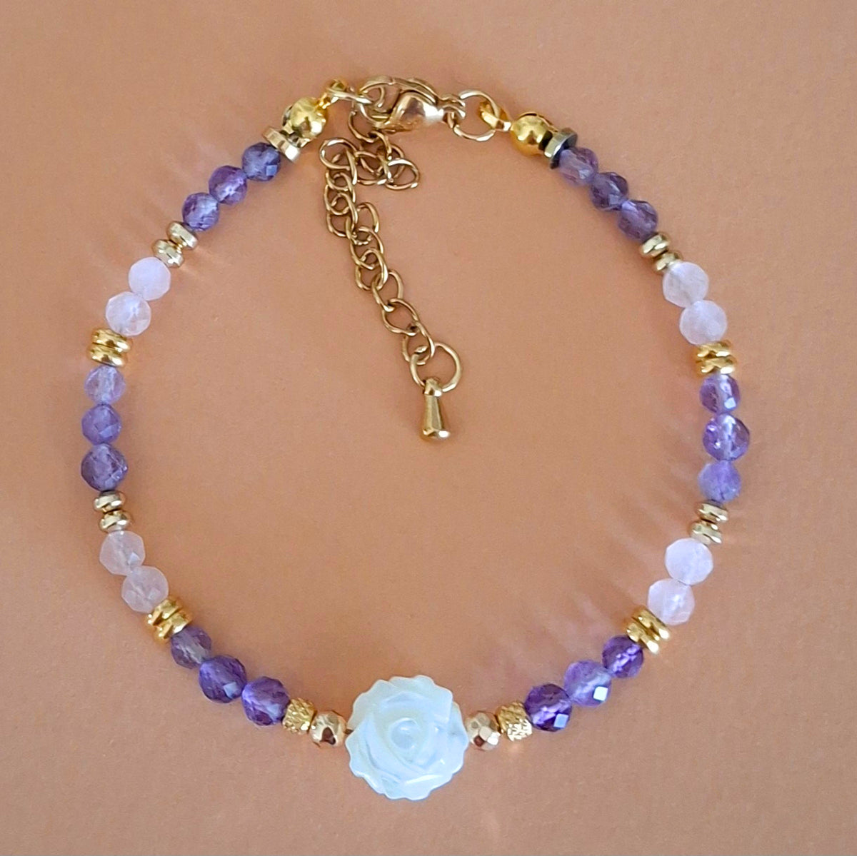 Bracelet Célia en perles facettées d'améthyste et de quartz rose, avec rose centrale en nacre et finitions dorées