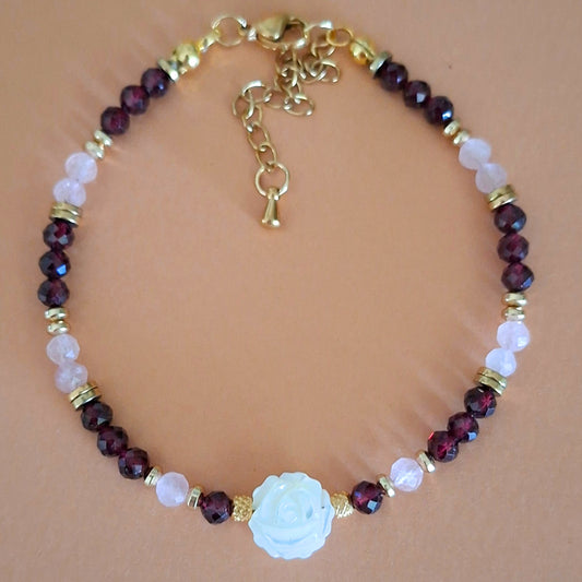 Bracelet Célia en perles facettées de grenat et quartz rose, avec rose centrale en nacre et finitions dorées