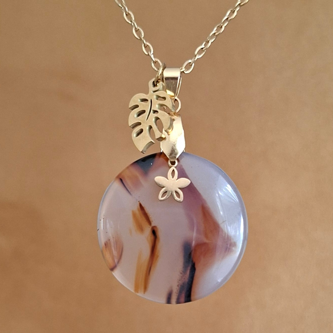 Collier en acier et agate ronde du Montana avec breloques fleur et feuille de monstera