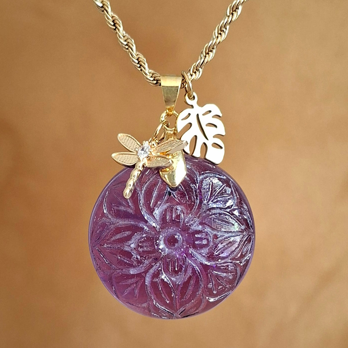 Collier acier doré en améthyste ronde ciselée aves breloques feuille et libellule