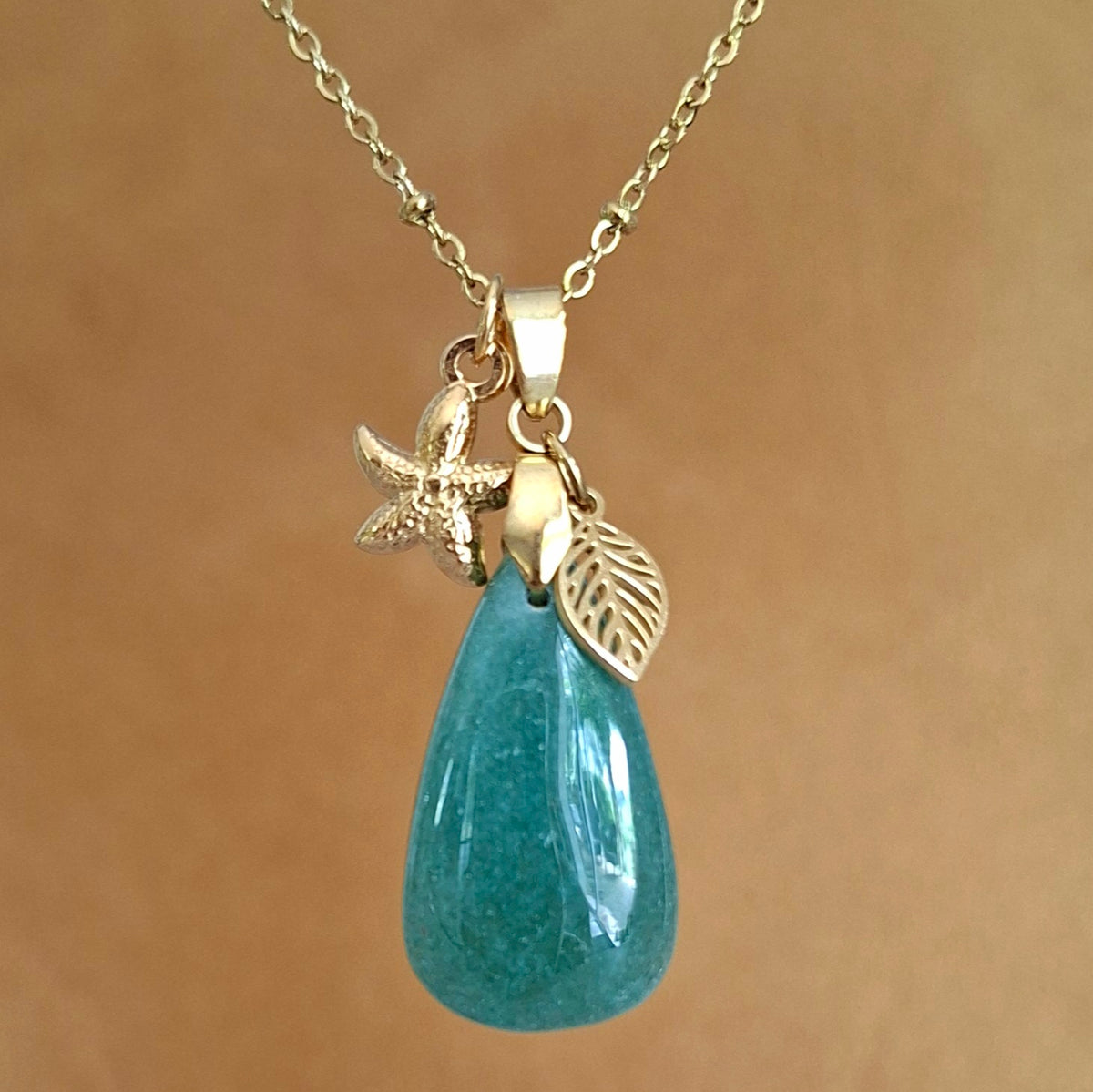 Collier en aventurine poire sur chaîne dorée maille perlée avec breloques étoile de mer et feuille.