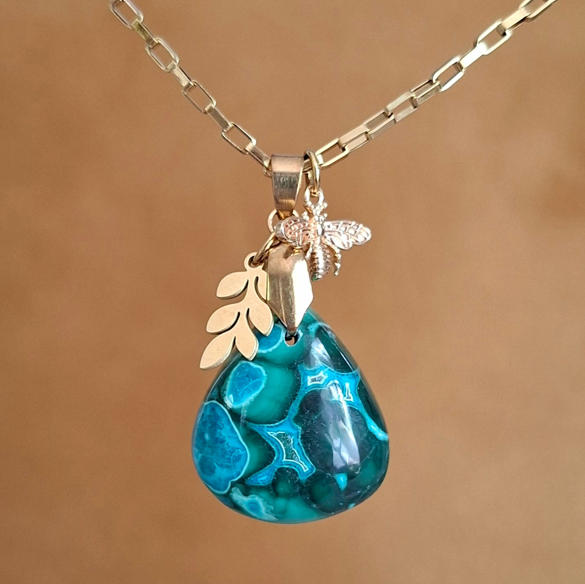 Collier en malachite chrysocolle avec breloque feuille et abeille sur chaîne dorée.