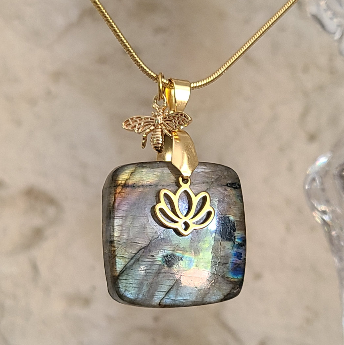 Collier en labradorite carrée aux reflets multicolores avec breloques abeille et lotus dorées. Petite Rainette Bijoux