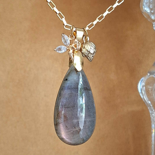 Collier en labradorite violette en forme de goutte avec breloques fée et bouton de lotus en acier doré. 
