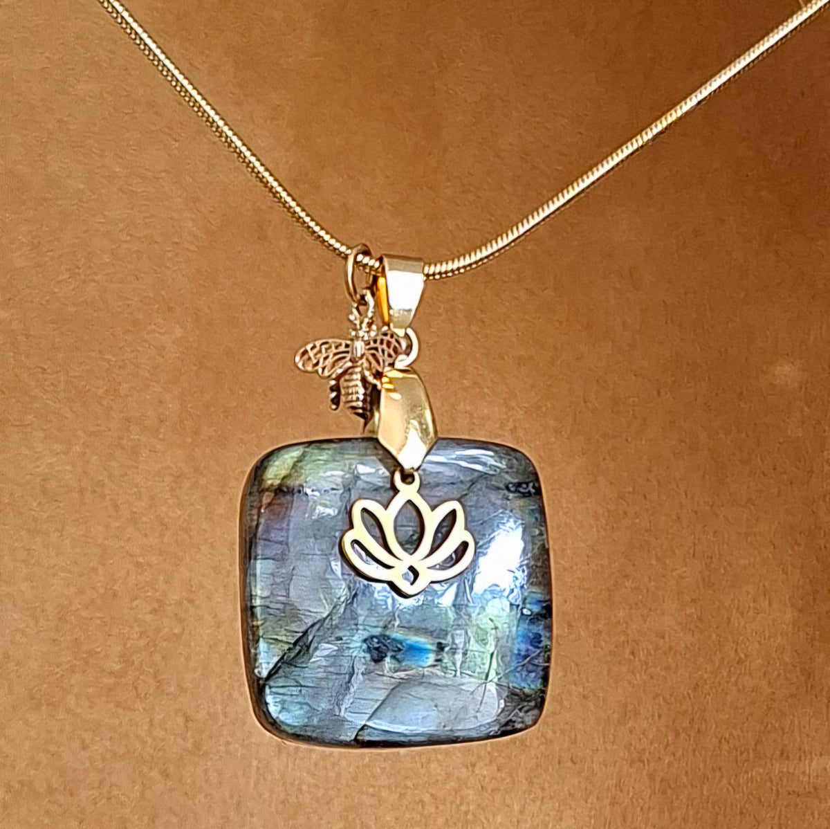 Collier en labradorite carrée aux reflets multicolores avec breloques abeille et lotus dorées. 