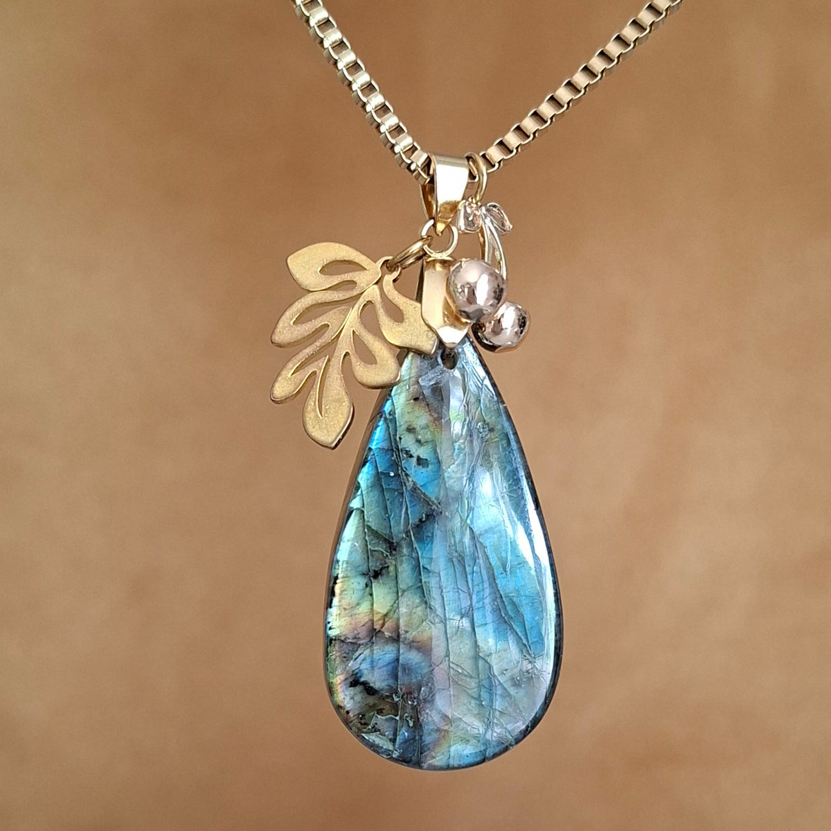 Collier en labradorite en forme de goutte avec breloques feuille et cerises en acier doré. 
