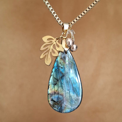 Collier en labradorite en forme de goutte avec breloques feuille et cerises en acier doré. 