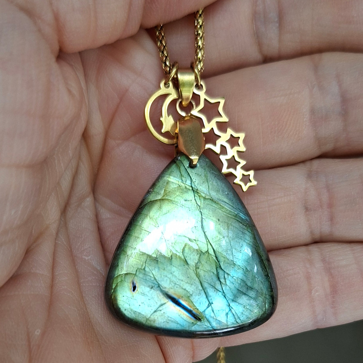 Collier labradorite verte dans la main avec breloques étoiles et lune