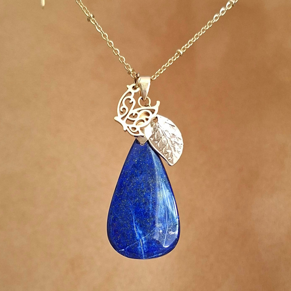 Collier acier en lapis-lazuli goutte avec breloques feuille et papillon.