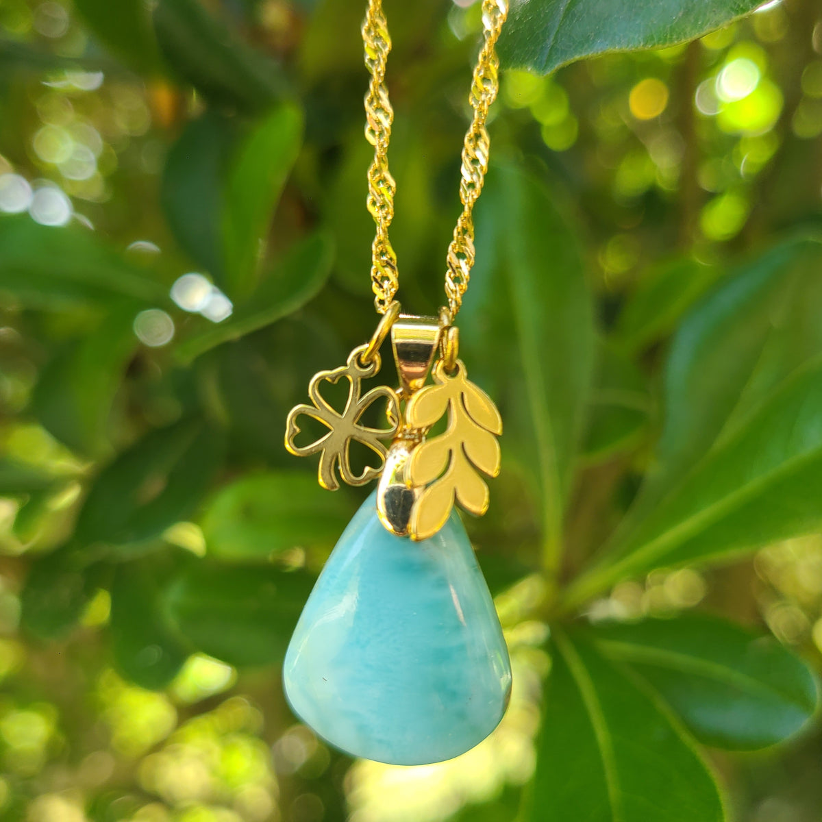Collier en acier inoxydable doré avec larimar bleu taillé en poire, breloques feuille et trèfle.