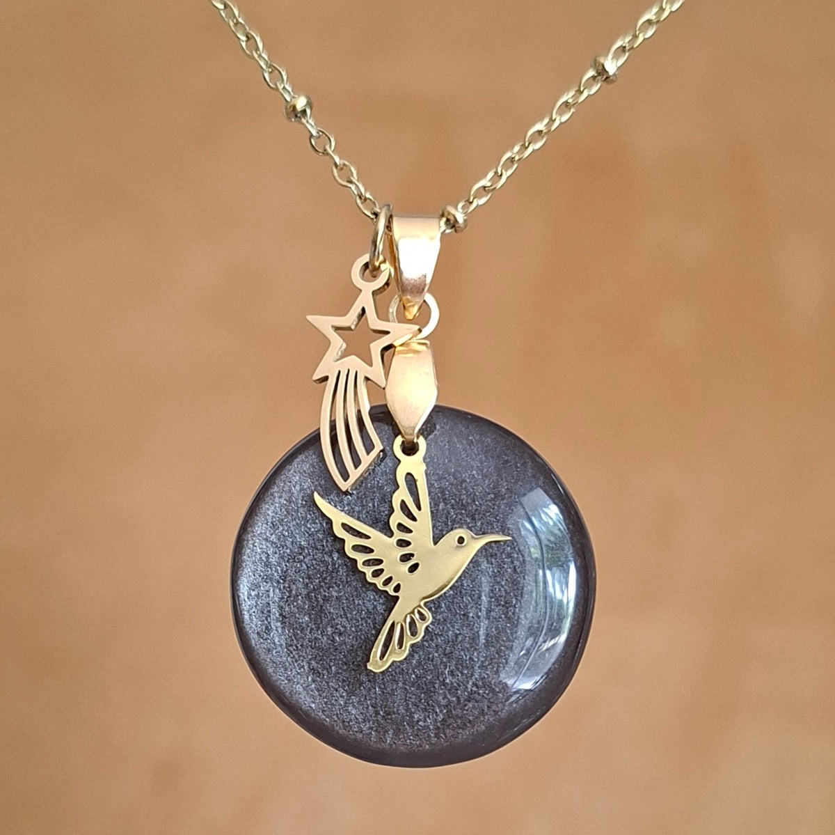 Collier en obsidienne argentée sur chaîne dorée maille perlée avec breloques colibri et étoile filante. 