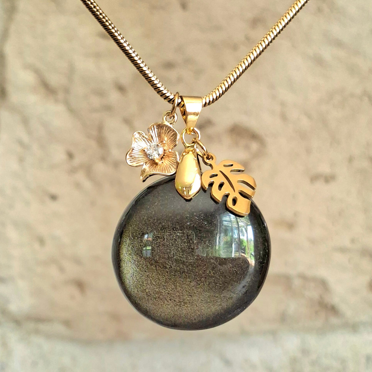 Collier en obsidienne dorée ronde sur chaîne acier doré avec breloques fleur et feuille