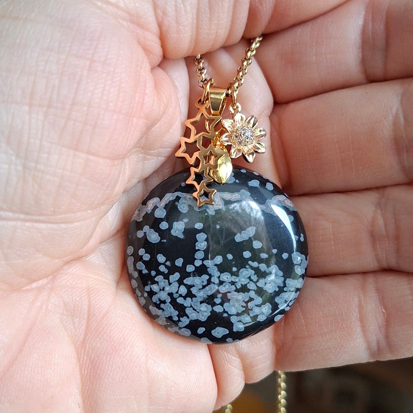 Collier en obsidienne flocon de neige ronde présenté dans la main, pièce unique.
