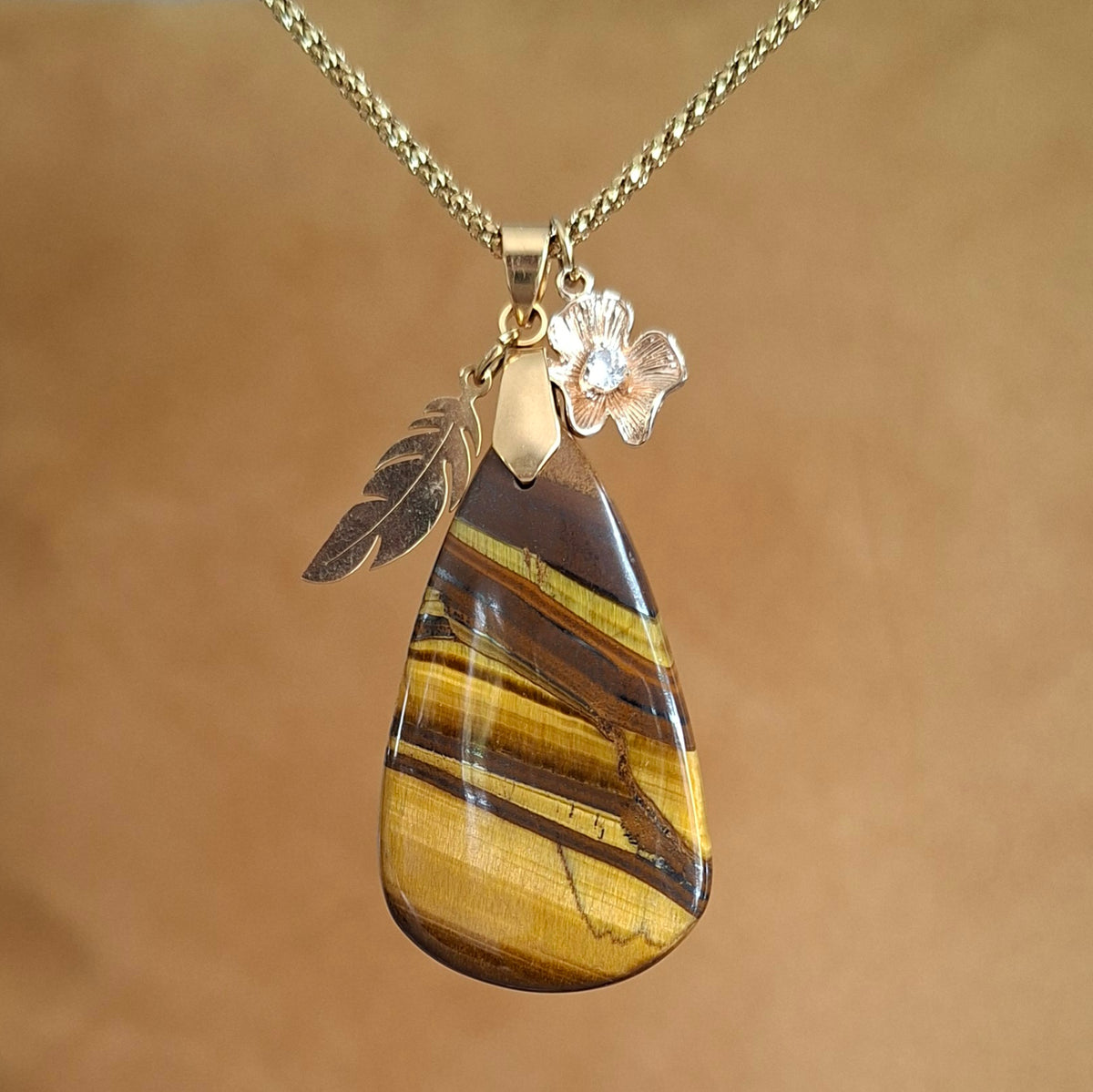 Collier acier doré et oeil de tigre forme poire avec breloques plume et fleur