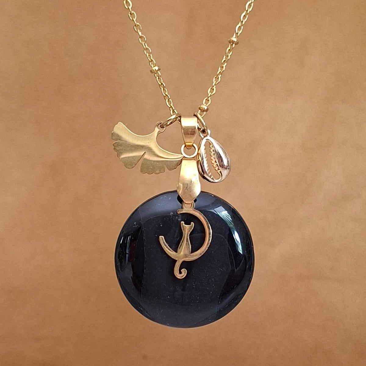 Collier en onyx noir rond sur chaîne dorée avec breloques chat ginkgo et coquillage