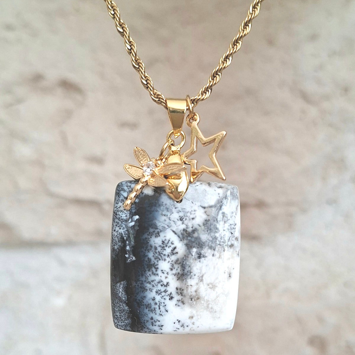 Collier en opale dendrite rectangulaire monté sur chaîne acier inoxydable doré avec breloques étoile et libellule.