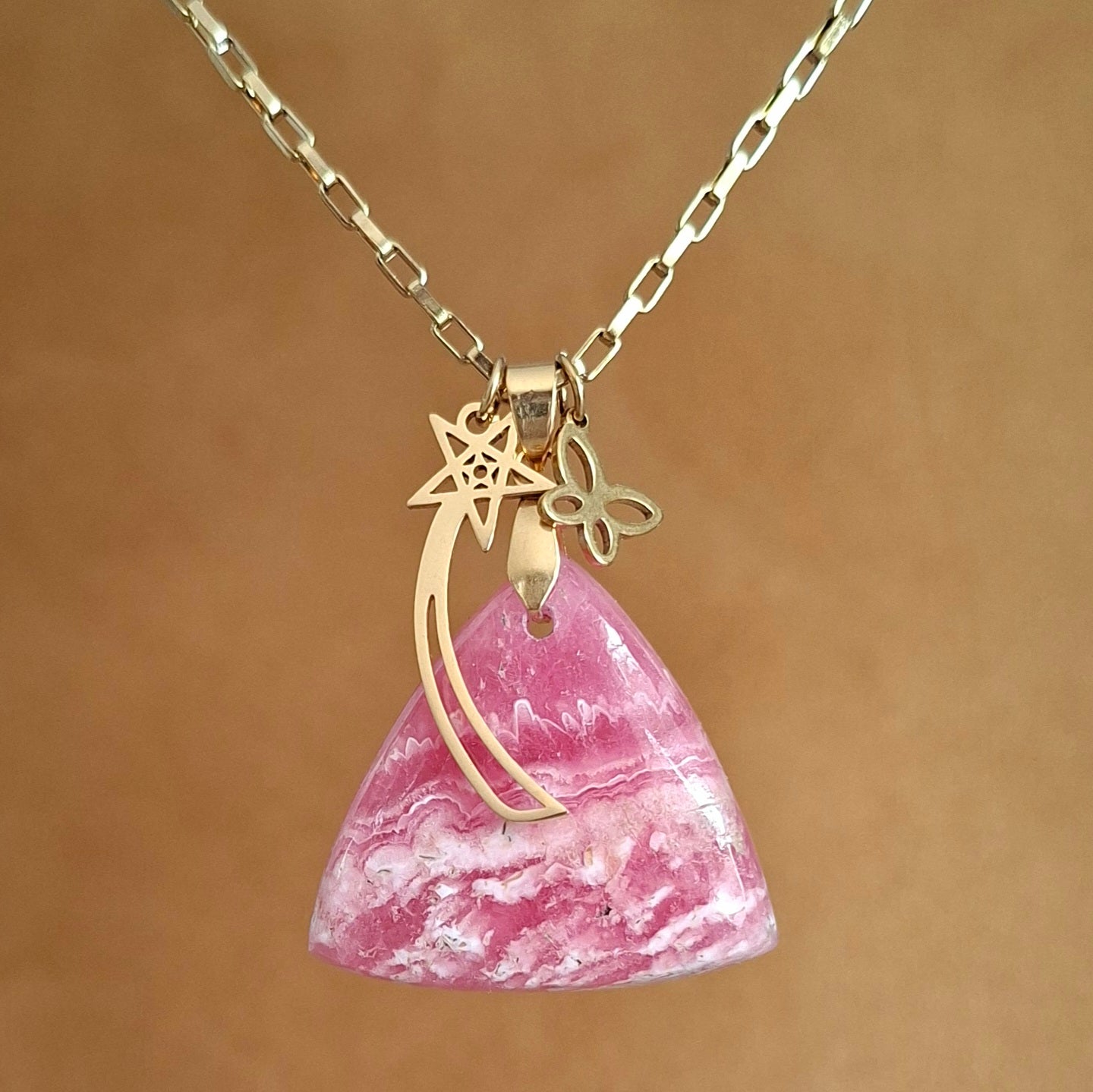 Collier en rhodochrosite naturelle triangulaire sur chaine acier doré avec breloques étoile filante et papillon.