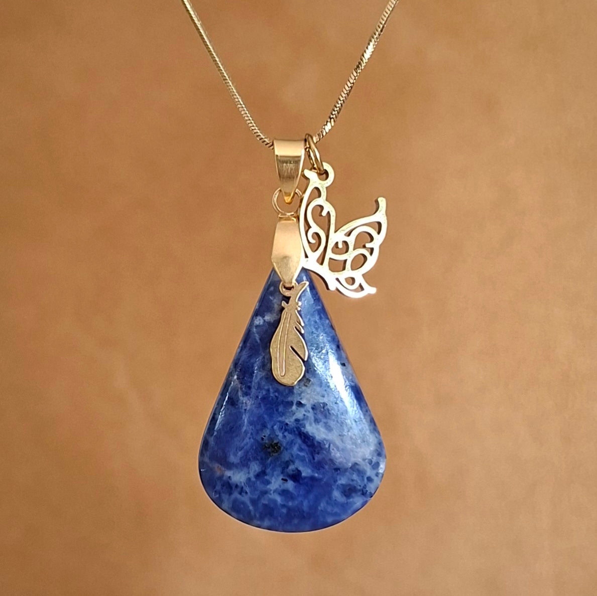 Collier en sodalite sur chaine acier doré avec breloques plume et papillo,