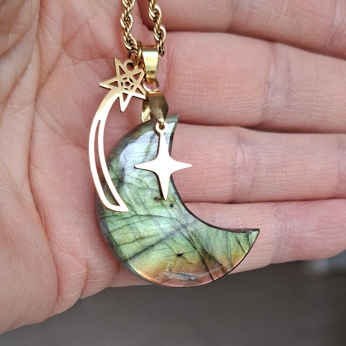 detail dans la main collier lune en labradorite verte et dorée. Petite Rainette
