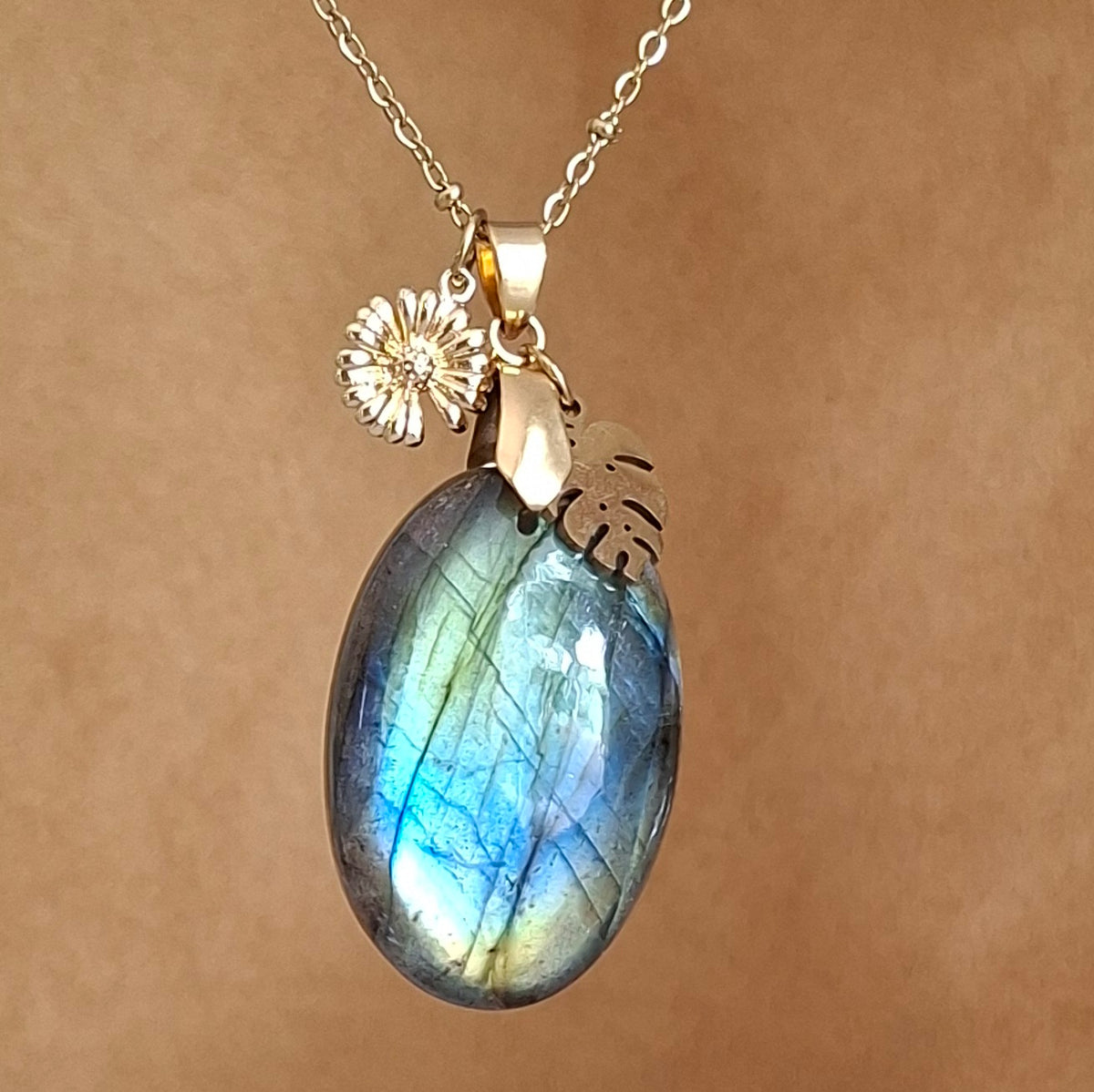 Collier en labradorite ovale aux reflets verts, bleus et dorés avec breloques monstera et tournesol 