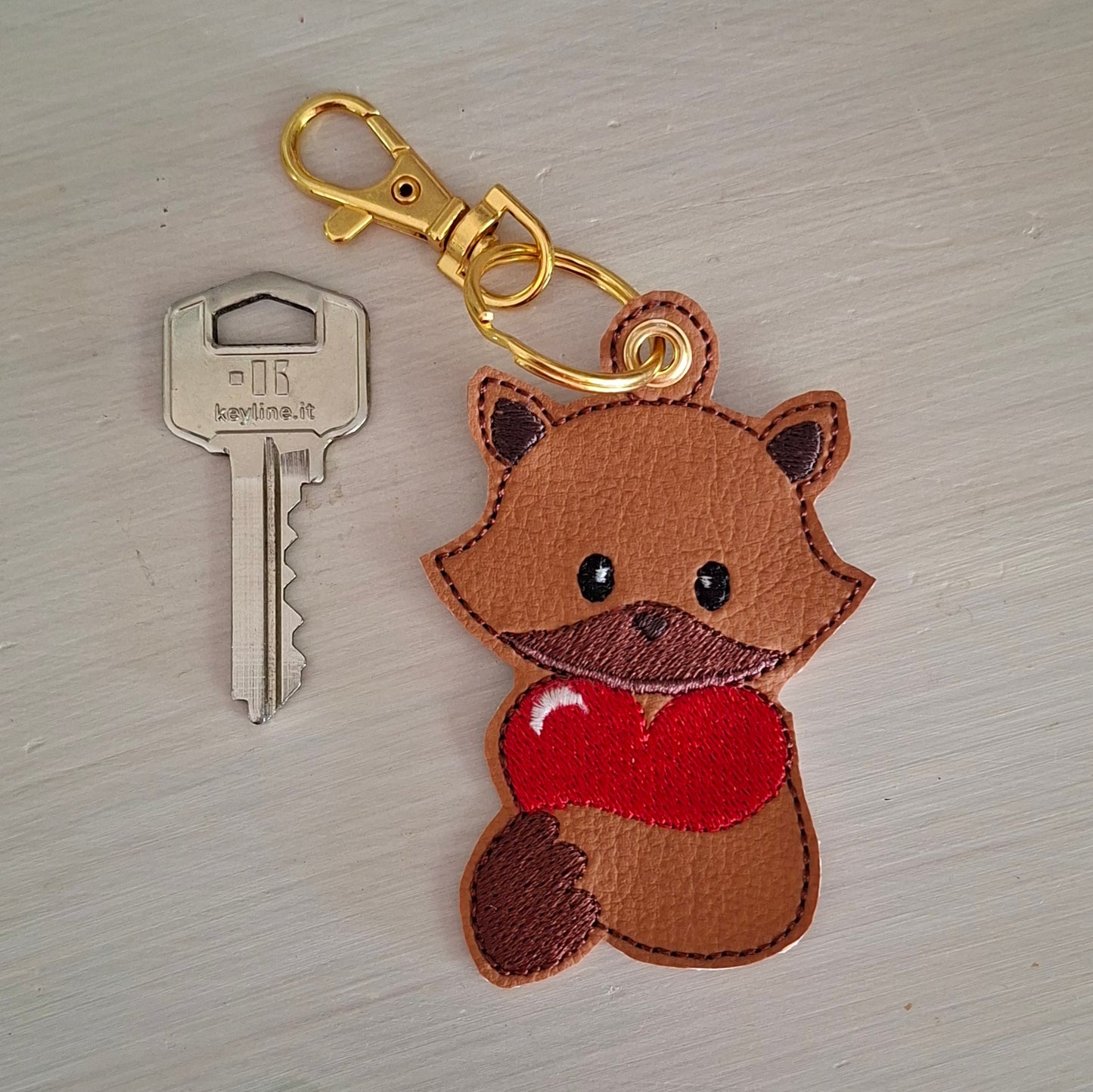 Porte-clés renard brodé présenté avec une clé