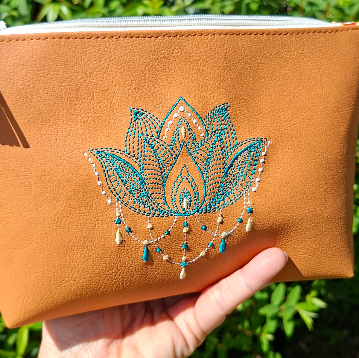 Trousse femme brodée lotus en simili cuir camel tenue en main