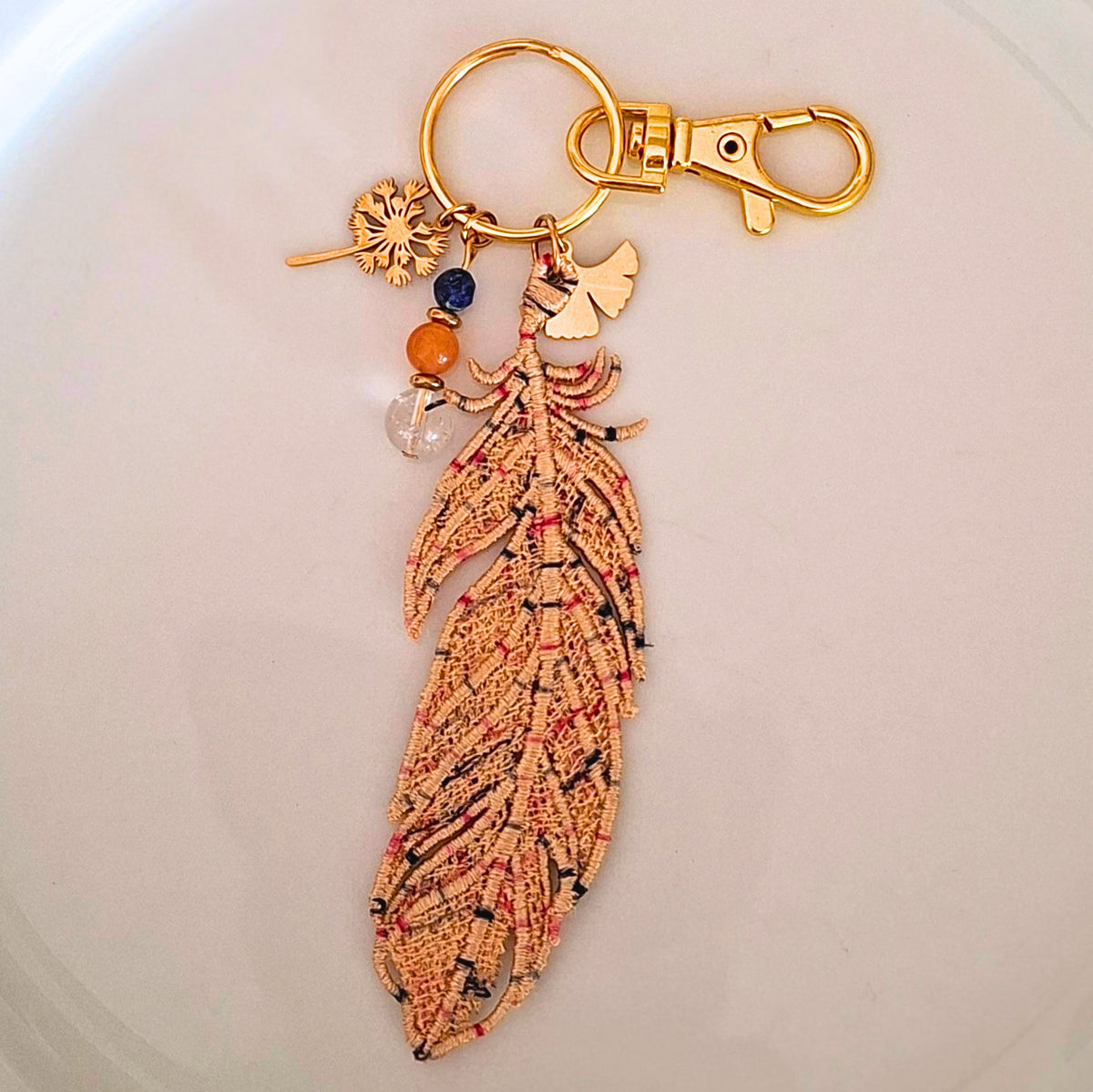 Bijou de sac Plume Liberté beige brodée avec quartz rutile, cornaline et lapis-lazuli