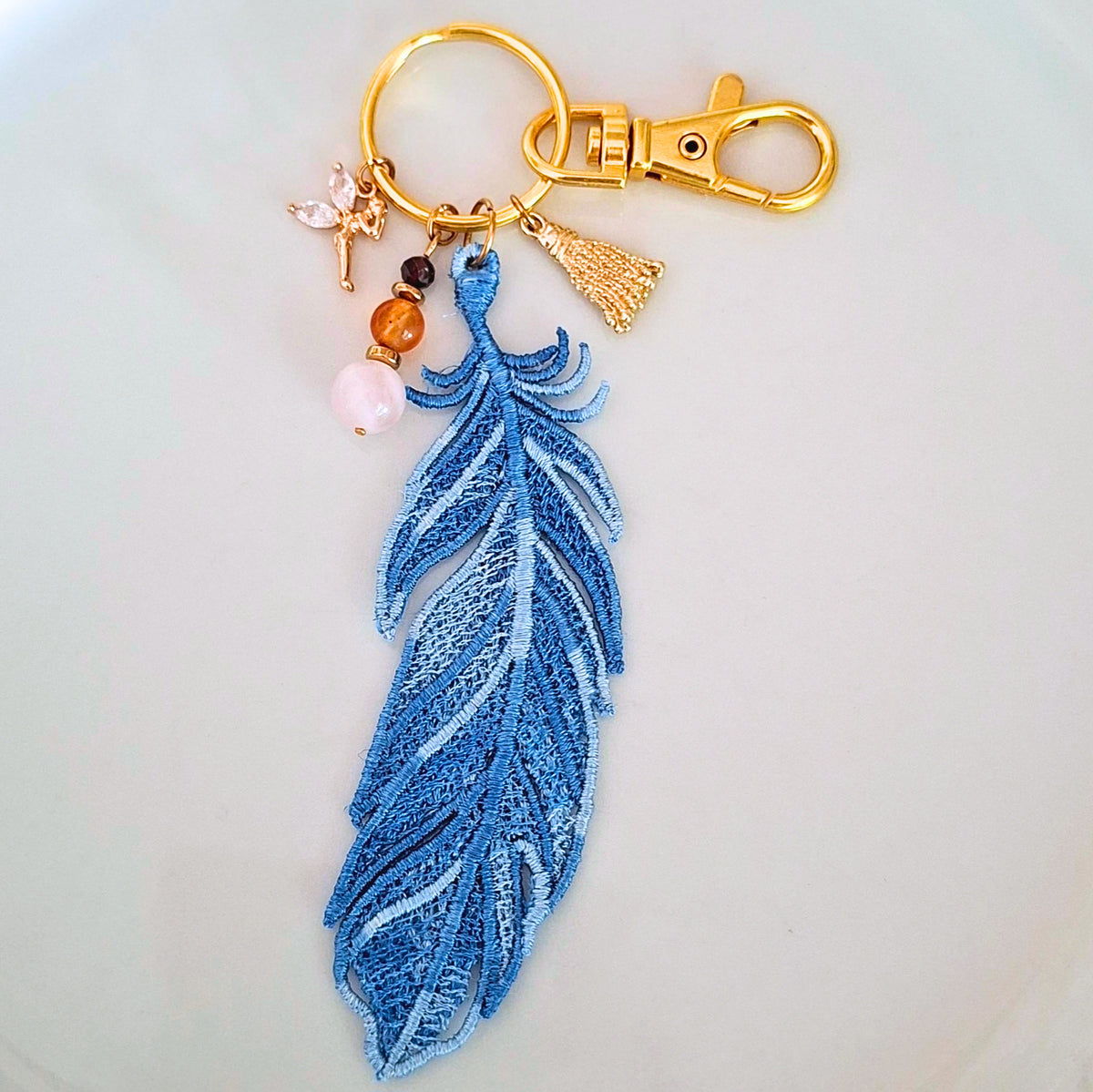Bijou de sac Plume Liberté bleue brodée avec quartz rose, cornaline et grenat