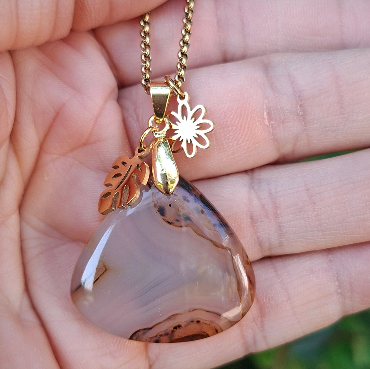 Collier en agate du Montana naturelle aux dessins beige et caramel présenté dans la main.