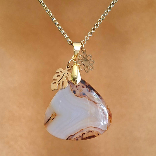 Collier en agate du Montana naturelle aux nuances crème et caramel avec breloques fleur et feuille dorées.