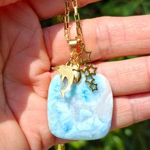 Charger l'image dans la galerie, Collier asymétrique en larimar carré présenté dans la main avec breloques dorées