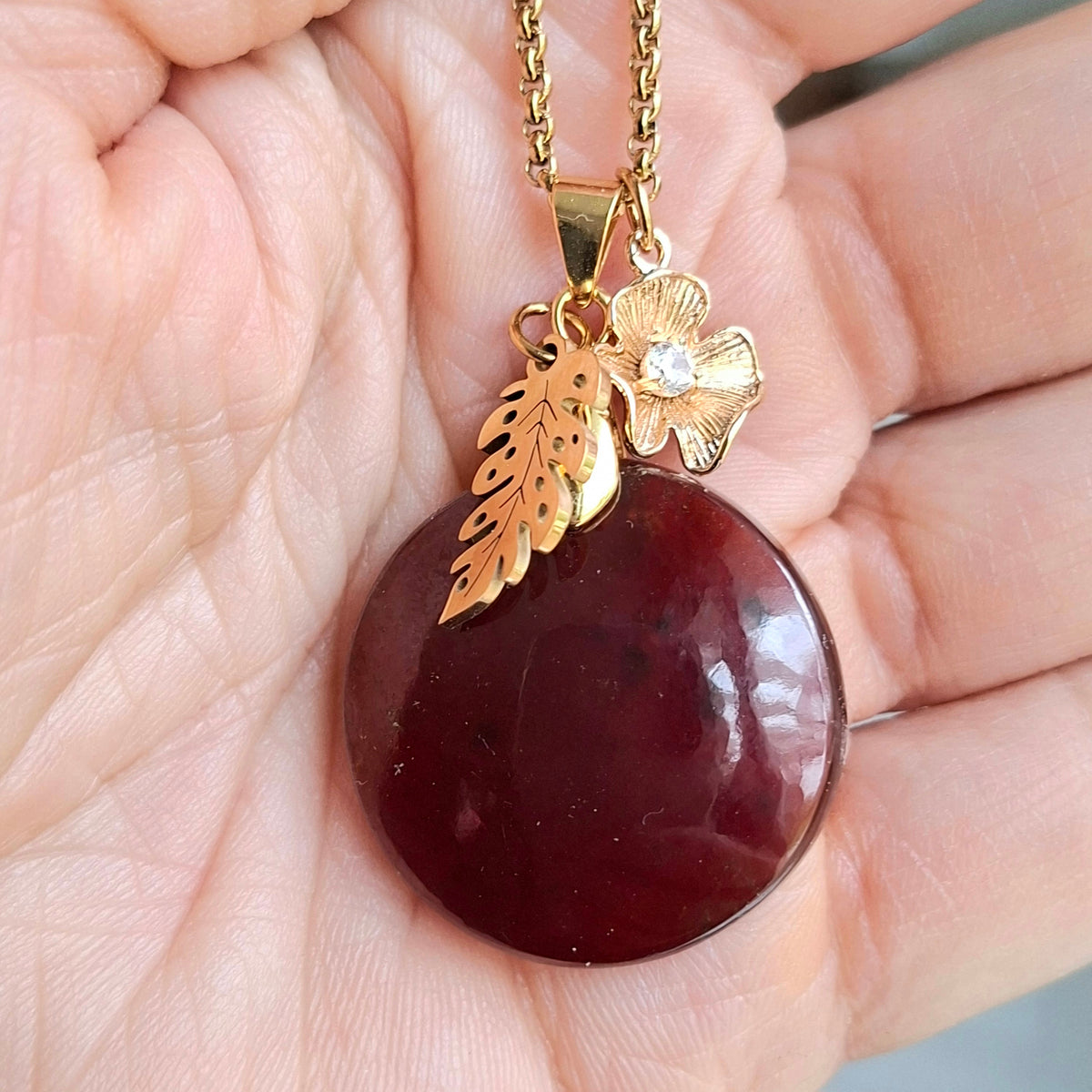 Collier grenat hessonite rond pierre naturelle acier inoxydable doré feuille fleur zirconium dans la main