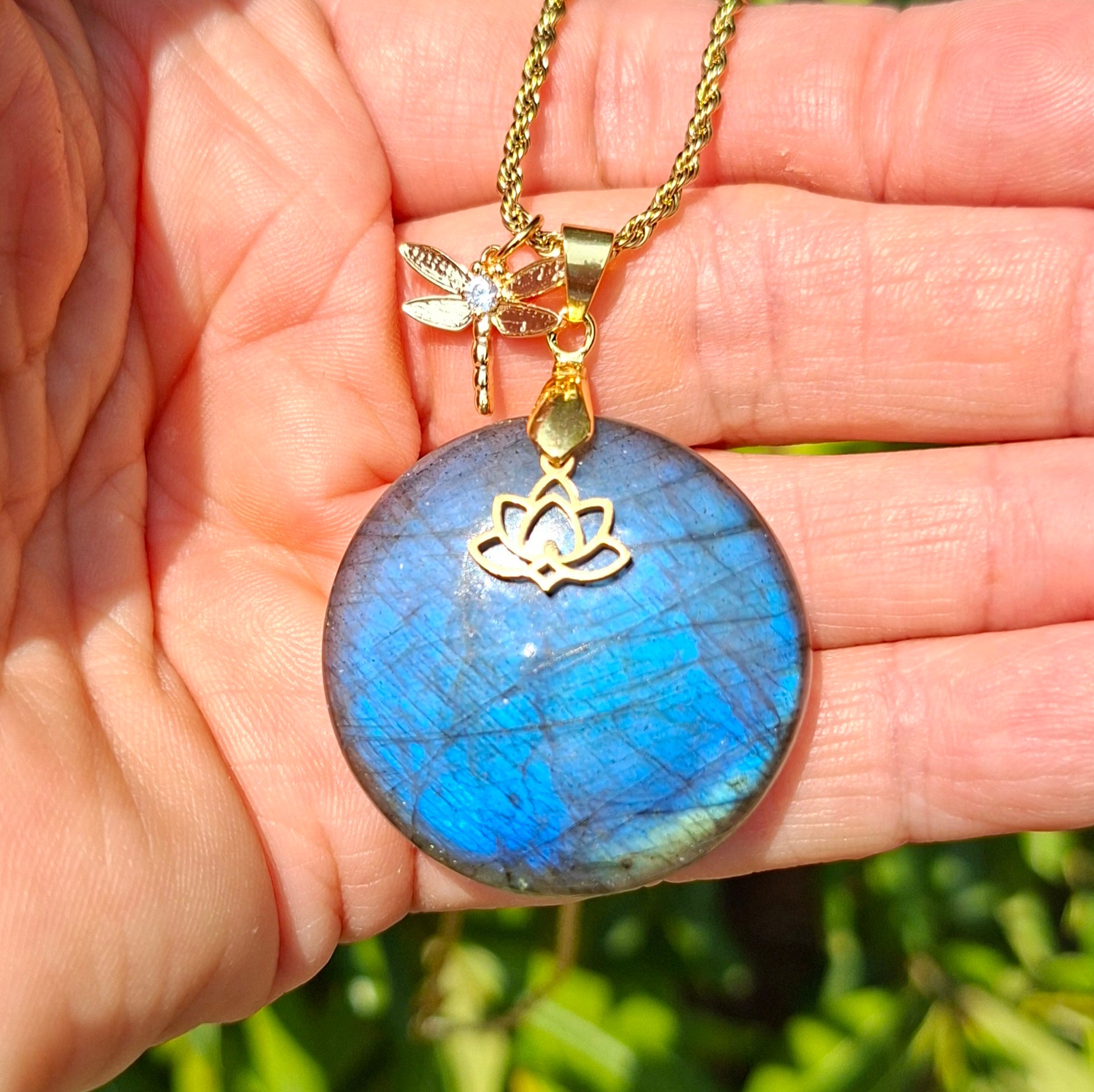 Collier en labradorite bleue ronde présenté dans la main avec breloques dorées
