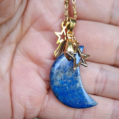 Collier lune en lapis-lazuli bleu nuancé présenté dans la main avec breloques étoile et étoile filante.
