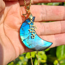 Charger l'image dans la galerie, Collier lune en labradorite tenu dans la main montrant ses reflets bleus