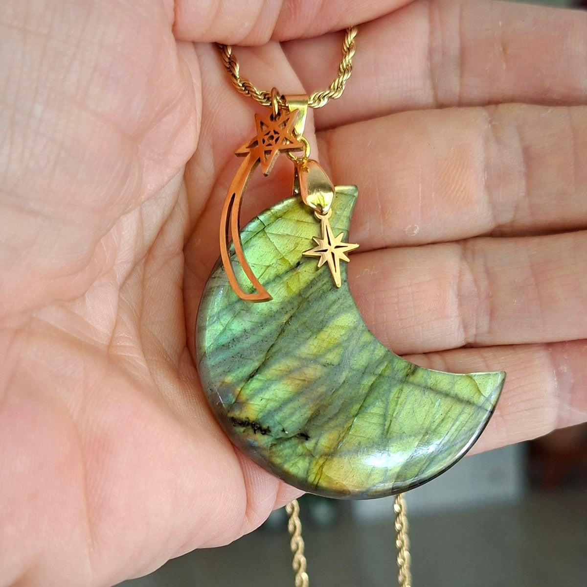 Collier lune en labradorite aux reflets verts et dorés présenté dans la main