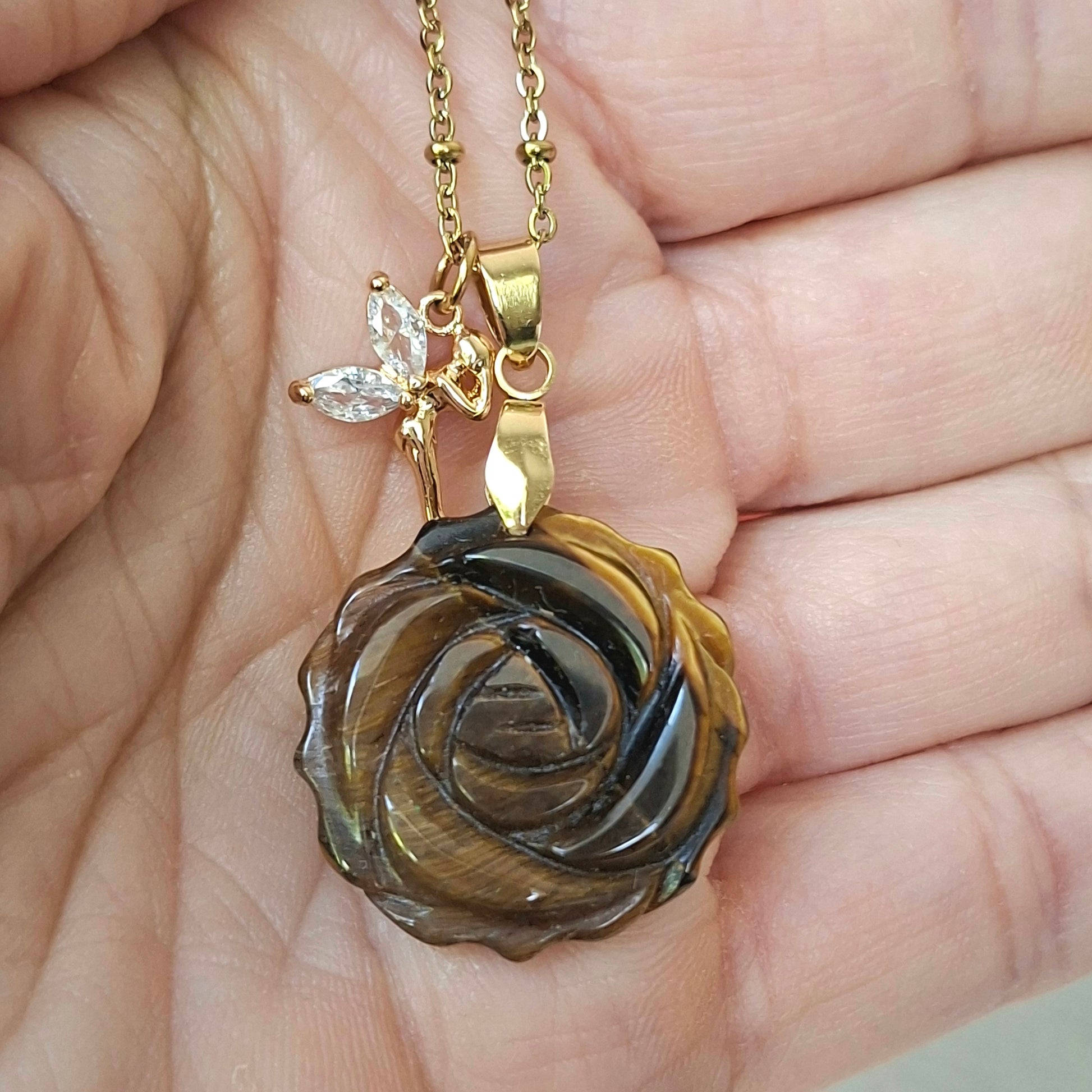 Collier en œil de tigre sculpté en rose présenté dans la main.