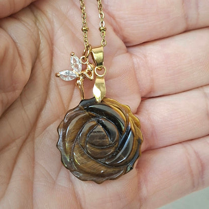 Collier en œil de tigre sculpté en rose présenté dans la main.