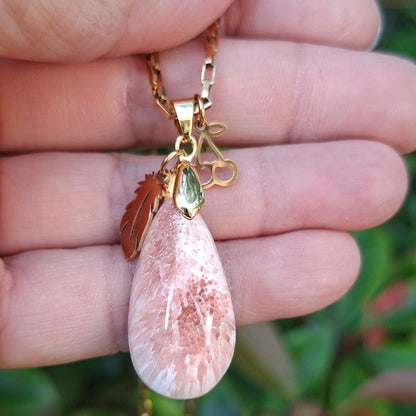 Collier en scolécite naturelle rose saumon aux reflets lumineux présenté dans la main.
