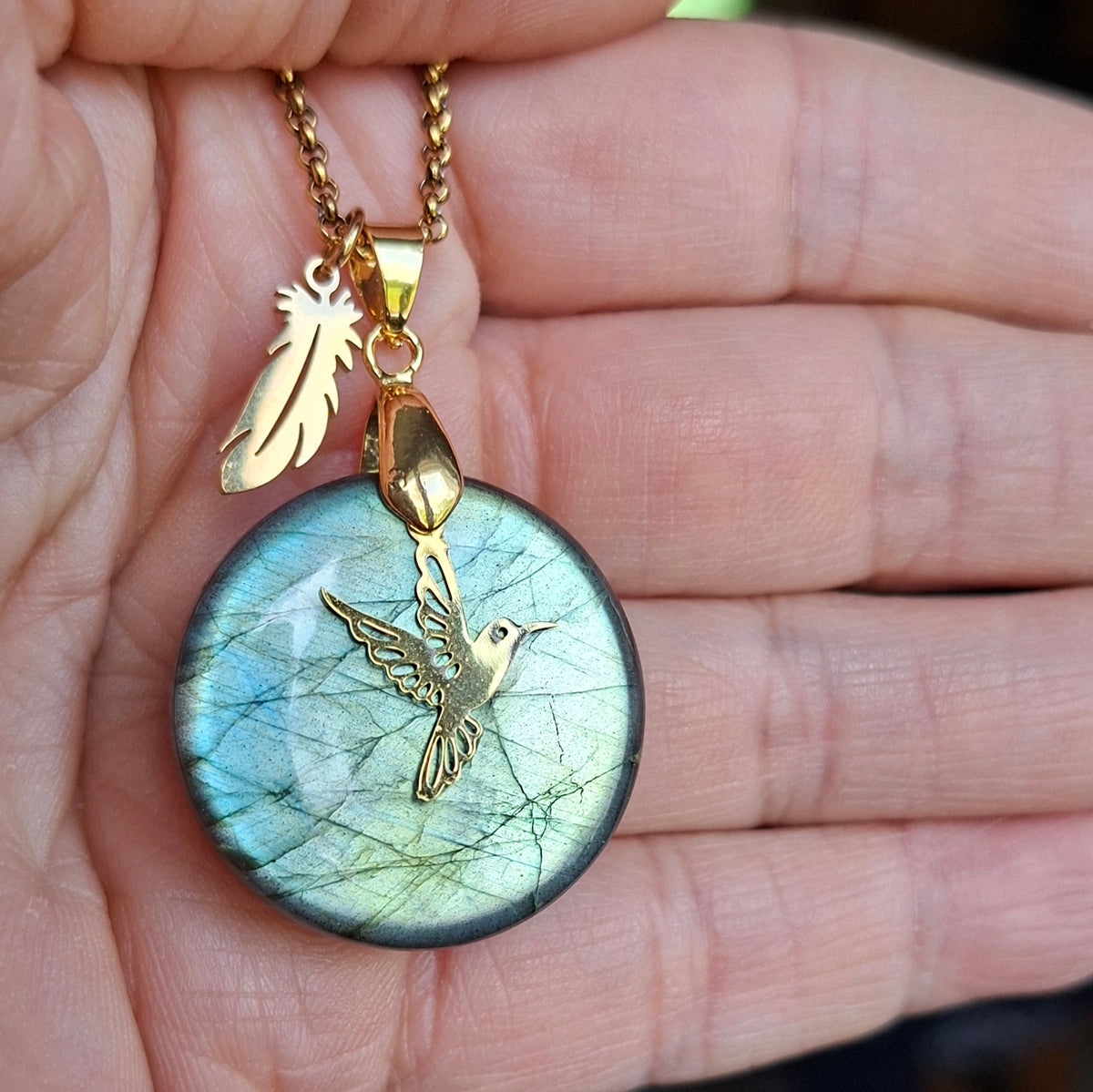 Collier en labradorite ronde présenté dans la main montrant ses reflets verts.